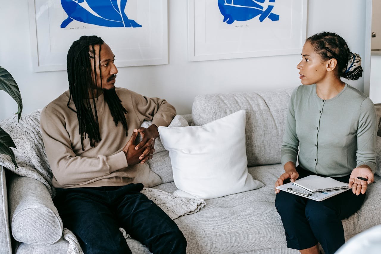 Professional therapy session indoors, with two adults focused on discussion and support.